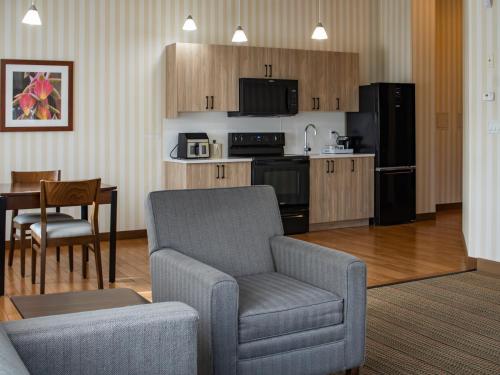 a living room with a couch and a chair and a kitchen at Prestige Prince George Lodge in Prince George