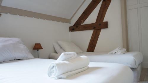 two white beds in a room with wooden beams at Le gîte du Canard boiteux in Silly