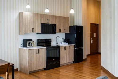 a kitchen with black appliances and wooden cabinets at Prestige Prince George Lodge in Prince George