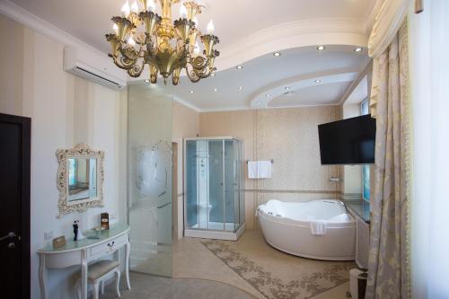 ロストフ・ナ・ドヌにあるベラージオ ホテルのバスルーム(バスタブ付)、テレビ、シャンデリアが備わります。