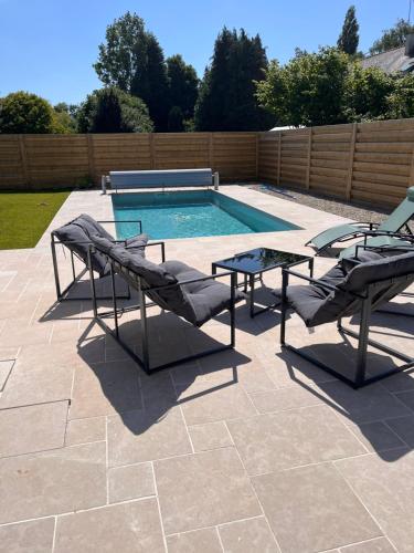 a patio with a pool with two chairs and a table at Chambres d'hôtes avec piscine chauffée de mai à sept ,TERRA COTTA et TAUPE in Lanvollon