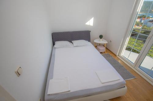 a white bed in a room with large windows at House Matilda in Primošten