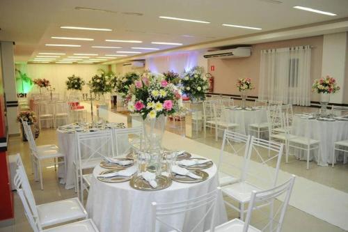 a banquet hall with white tables and chairs and flowers at Hotel São Bento in Marabá