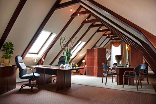 an attic room with chairs and tables and windows at Rezydencja Solei Old Town in Poznań