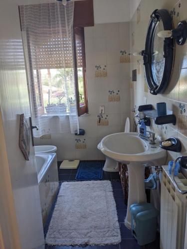 a bathroom with a sink and a tub and a mirror at La Lampara sul Mare in Torrenova