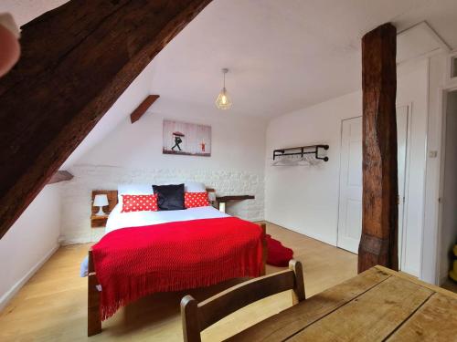 a bedroom with a bed with a red blanket at La Pagerie in Maupertuis