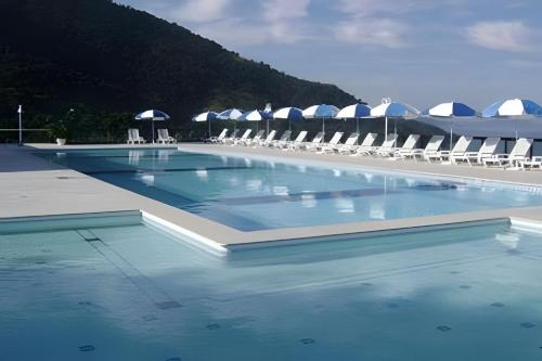 a swimming pool with chairs and umbrellas at PORTO REAL RESORT - APARTAMENTO VISTA MAR EM CONDOMÍNIO COM PRAIA PRIVATIVA in Mangaratiba