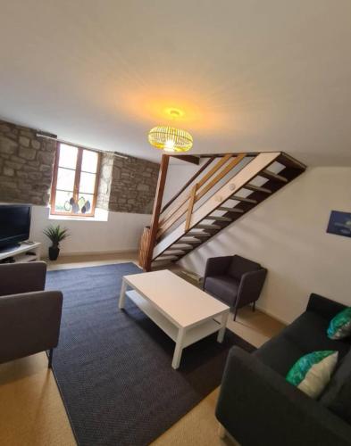 a living room with a table and a staircase at La Pagerie in Maupertuis