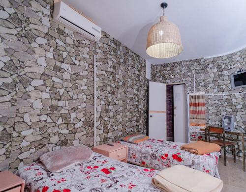 a bedroom with two beds and a stone wall at ksar el afia in Jendouba