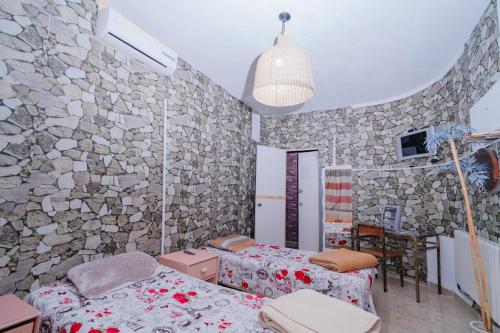 a bedroom with two beds and a stone wall at ksar el afia in Jendouba