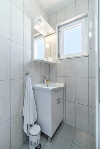 a white bathroom with a sink and a mirror at Korak Do Mora in Murvica