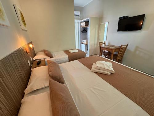 a hotel room with two beds and a television at Hotel Vicino al Mare - Frente mar in Guarujá