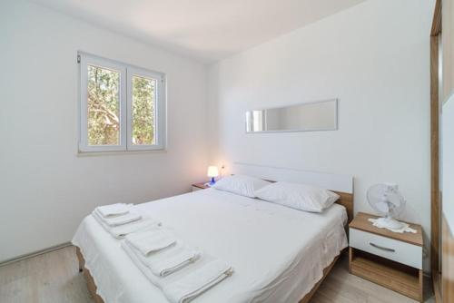 a bedroom with a large white bed with a window at Korak Do Mora in Murvica