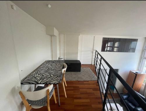 Cette chambre dispose d'une table, de chaises et d'un balcon. dans l'établissement Charmant Duplex aux Portes de Paris, à Ivry-sur-Seine