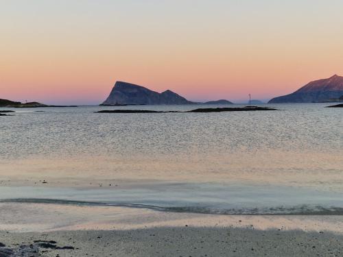 a beach at sunset with mountains in the background at Warm and cosy apartment in Tromsø