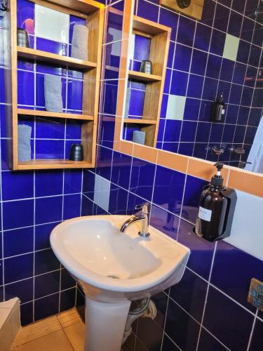 a blue tiled bathroom with a sink and a mirror at Barrbra BnB Over The Sea in Bocas del Toro