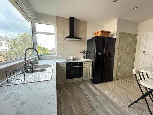 eine Küche mit einem schwarzen Kühlschrank und einer Spüle in der Unterkunft Harbour Mill Cottage in Annalong