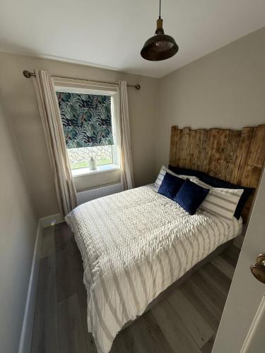 a bed in a bedroom with a window at Harbour Mill Cottage in Annalong