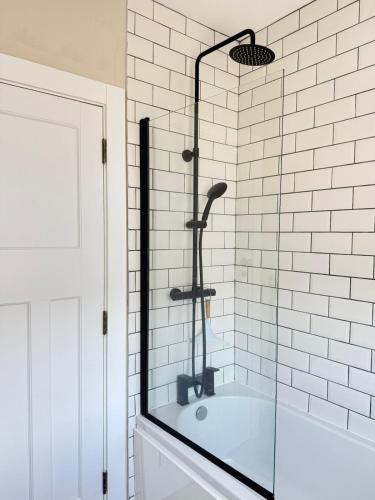 a glass shower in a bathroom with a tub at Harbour Mill Cottage in Annalong