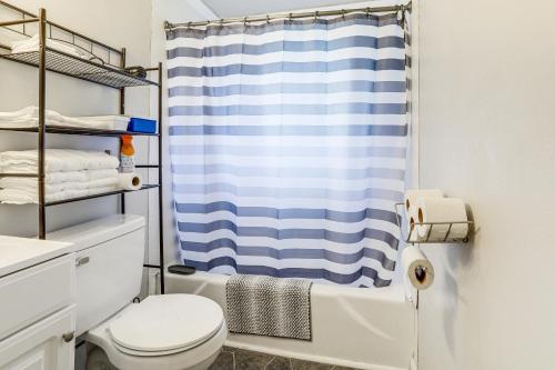 a bathroom with a blue shower curtain and a toilet at 14 Mi to Downtown Baton Rouge Plaquemine Retreat in Plaquemine