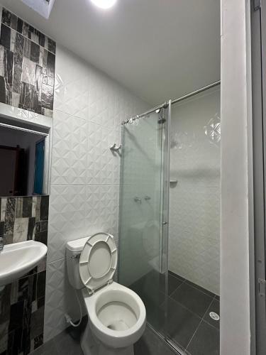 a bathroom with a toilet and a glass shower at Hotel Buenos Aires in Pasto