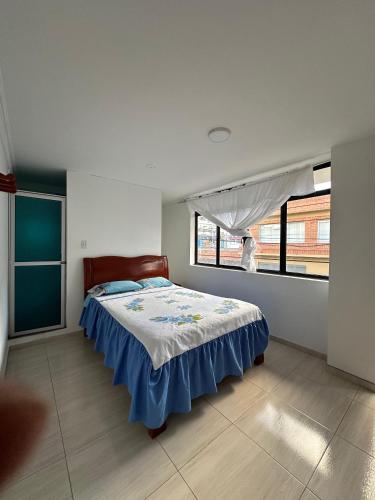a bedroom with a bed with a blue and white blanket at Hotel Buenos Aires in Pasto