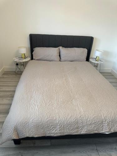 a bed with a black headboard and two side tables at Flat in London in Uxbridge
