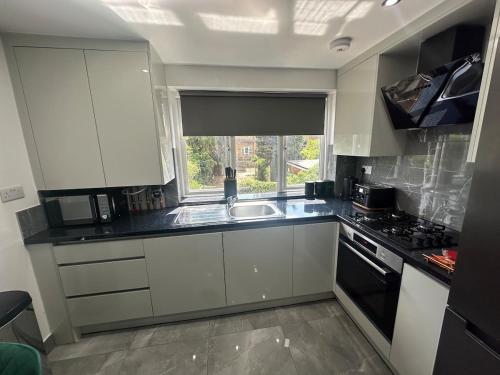 a kitchen with white cabinets and a sink and a window at Flat in London in Uxbridge