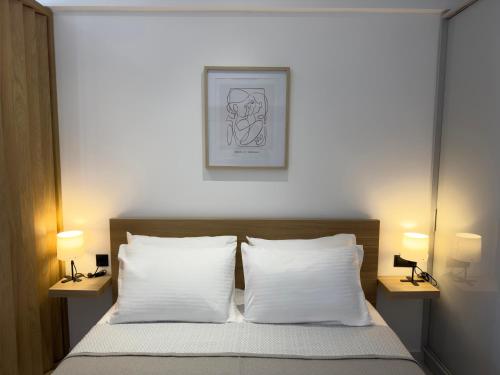 a bedroom with a bed with white pillows and two lamps at Mare Luxury Studios in Kallithea Halkidikis
