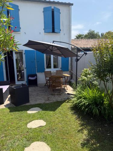 un patio con una mesa y una sombrilla en Maison tout confort 4 personnes port des salines 3 étoiles 2025, en Grand-Village-Plage
