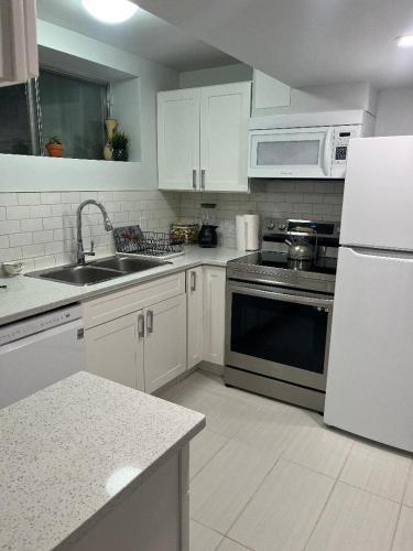 a kitchen with a sink and a stove top oven at Cozy and comfy 1 BEDROOM basement suite at Cougar ridge SW Calgary in Calgary