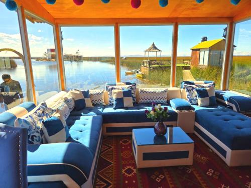 a living room with blue couches and a view of the water at UROS KAY PACHA Lodge in Puno