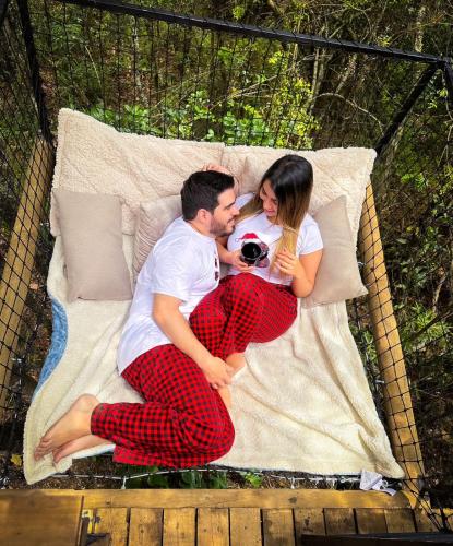 a man and a woman sitting on a bed at Cabaña Lambrusco - La Cava Lodge in Medellín