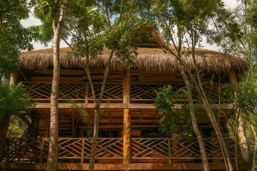 een bamboehuis met een rieten dak en bomen bij Treehouse Tulum H2Ojos in Tulum