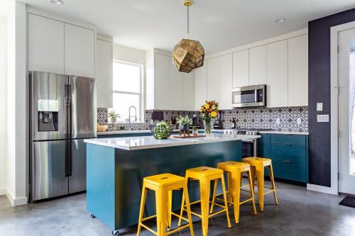 a kitchen with a blue island with four yellow stools at Electric Disco Den - 6 Min Walk to Rainey St in Austin