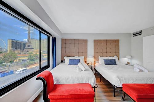 two beds in a room with a large window at Stay Together Suites - Condominium Sleeps 9 With Strip View - NO RESORT FEES in Las Vegas