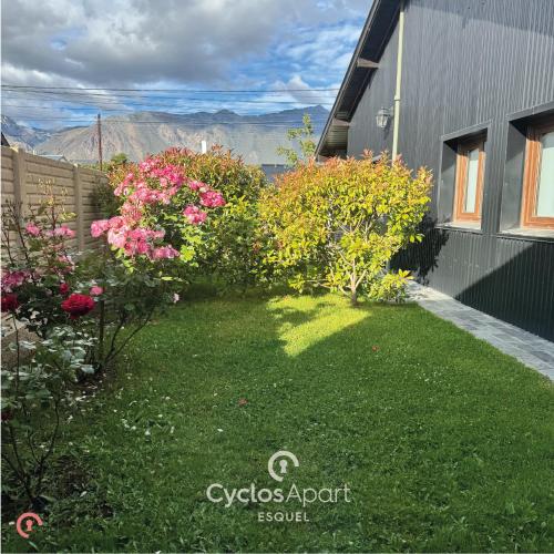 ein Garten mit rosa Blumen und ein Gebäude in der Unterkunft CyclosApart in Esquel