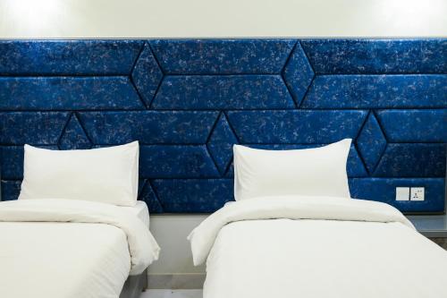 two beds in a room with a blue wall at Ocean Pearl Hotel in Karachi