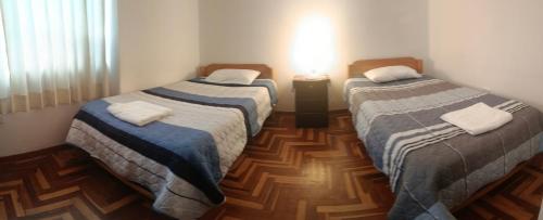 two beds in a room with wooden floors at WaskarWasi in Cusco