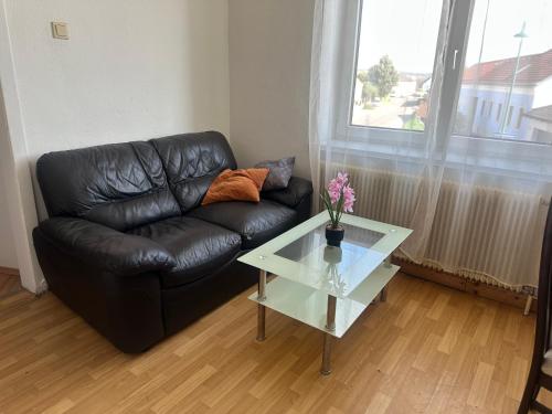 a living room with a black leather couch and a glass table at Privatzimmer Mama in Tresdorf