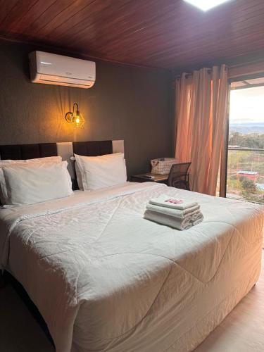 a bedroom with a large bed with towels on it at Pousada Recanto Querubins in Paty do Alferes