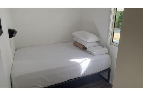 a white bed with two pillows and a window at Discovery Parks - Tannum Sands in Tannum Sands