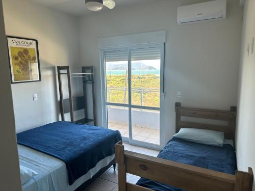 a bedroom with two beds and a window with a view at Villa Cavaliere in Palhoça