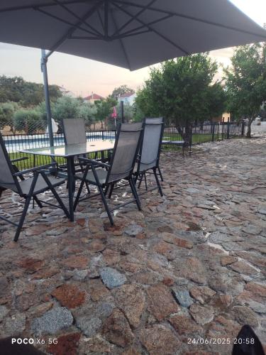 a group of chairs and a table with an umbrella at Tapada das Carvalhas in Castelo Branco