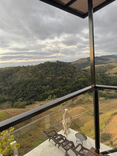 a balcony with a bench and a view of the countryside at Pousada Recanto Querubins in Paty do Alferes