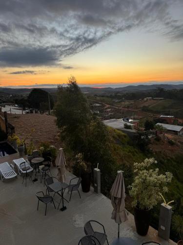 a patio with tables and chairs and a sunset at Pousada Recanto Querubins in Paty do Alferes
