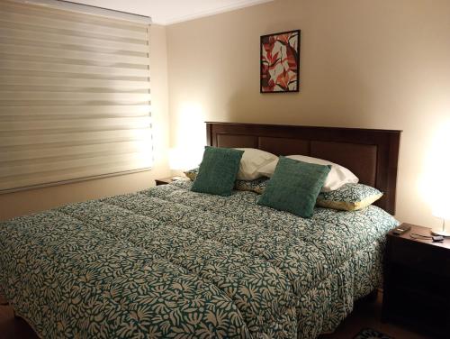 a bedroom with a bed with green pillows at Arriendo 1 Departamento Diario Amoblado en Edificio Pleno Centro de Osorno Full Eléctrico y Estacionamiento Techado, Comodidad, Moderno y Seguridad in Osorno