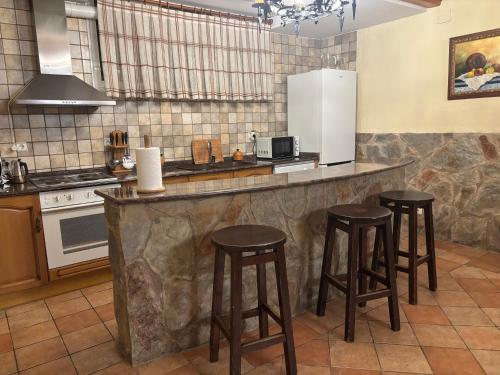 a kitchen with three bar stools at a counter at La casa de Serafín y Manoli in Nestares