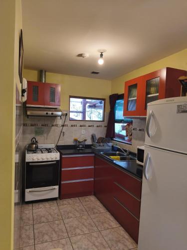 a kitchen with red cabinets and a white refrigerator at Hostal el Arroyito in Ushuaia