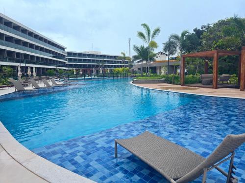 ein großer Pool mit Stühlen und ein Hotel in der Unterkunft Beach Class Summer Residence em Porto de Galinhas in Porto De Galinhas